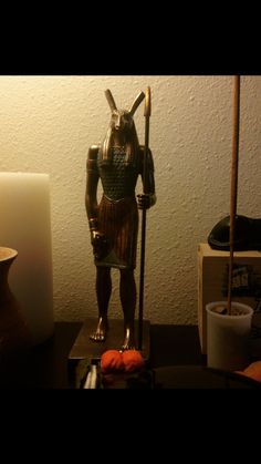 a statue of an egyptian god is on a table next to a lamp and other items