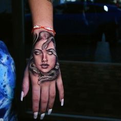 a woman's hand with a tattoo on it and a snake wrapped around her wrist