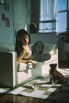 a woman laying on a couch next to a small dog