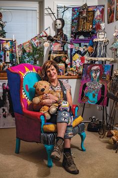 a woman sitting in a colorful chair holding a teddy bear and smiling at the camera