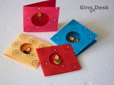 four different colored cards with buttons and holes in the middle, on a white surface