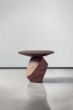 a wooden table sitting on top of a white floor in front of a gray wall