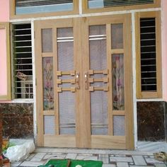 two wooden doors sitting next to each other in front of a pink building with windows