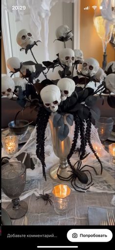 a table topped with lots of fake skulls and black spider webs next to candles