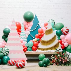 an assortment of balloons and christmas trees are displayed on a table with other holiday decorations