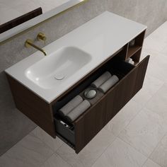 a bathroom sink sitting under a mirror next to a wooden cabinet with two rolls of toilet paper in it