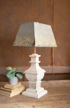 a white lamp sitting on top of a wooden table next to a potted plant