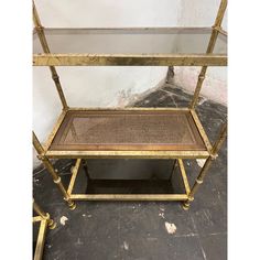 a gold metal and glass shelf on wheels