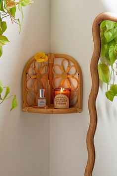 a wooden shelf with candles on it next to a potted plant in a corner