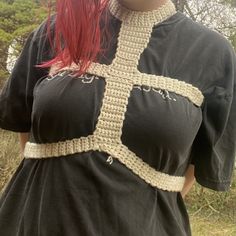 a woman with red hair wearing a crocheted shirt and holding an umbrella over her head