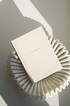 a book sitting on top of a white paper plate next to a shadow cast wall