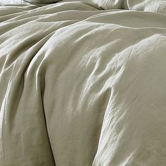 an unmade bed with white sheets and pillows