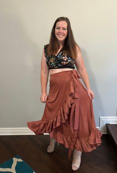 a woman standing in front of a wall wearing a skirt