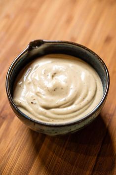 a close up of a bowl of food on a wooden table with a spoon in it