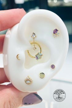 a person holding an earring in their hand with jewels on it and other jewelry