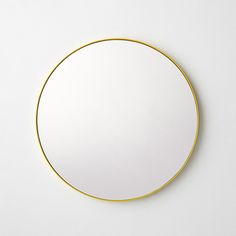 a round mirror sitting on top of a white wall next to a black and yellow object