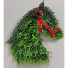 a horse head made out of evergreen leaves and red ribbon with pine cones on it