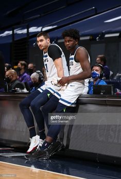 two basketball players sitting on the bench during a game