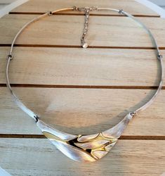 A vintage Birks sterling silver choker with two tone centrepiece adjustable 15 to 17 inches. SKU-1862 This exquisite vintage Birks necklace consists of a boomerang-shaped brushed centre, with a raised high polished gold tone leaf-like outline.. A jump ring at each end of the central piece connects to a flat brushed surfaced  arched link. There are 2 of these arched links on each side of the centre piece and 2 smaller arched links at each end.  Each link attaches to the next with a jump ring allo Retro Adjustable Silver Necklace, Vintage Adjustable Double Strand Necklace, Festive Dual-tone Metal Necklace, Vintage Double Strand Metal Necklace, Two Tone Jeans, Nickel-free Vintage Metal Choker, Vintage Multi-strand Metal Necklace, Double B, Sterling Silver Choker