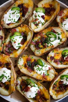 baked potato shells with bacon, cheese and green peppers on a white plate topped with sour cream