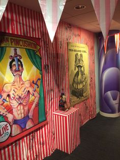 an office decorated with circus themed posters and striped wall coverings, including one man's torso