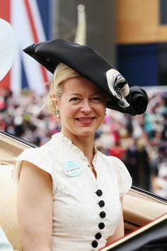 a woman in a black and white hat smiles as she sits in the back of a car