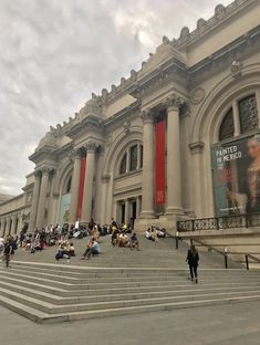 many people are sitting on the steps in front of an old building