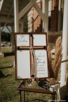 a wooden cross sitting on top of a table next to a white sign that says the coming