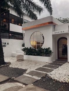 a white building with a circular window and palm trees in the front yard at dusk