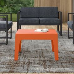 an orange coffee table sitting on top of a wooden floor next to two black couches