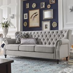 a living room filled with furniture and framed pictures on the wall above it's windows