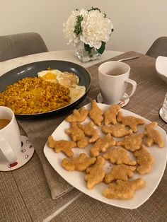 a plate of dog biscuits next to a bowl of eggs and coffee on a table