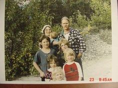 an old photo of a family posing for a picture in front of some bushes and trees