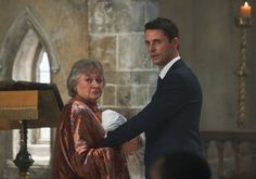 a man and woman standing next to each other in front of a church with candles