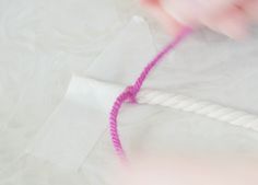 someone is making something with pink thread and white paper