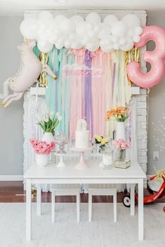 a table with balloons, cake and flowers on it