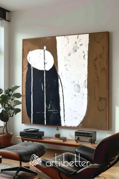 an abstract painting hangs on the wall above a leather chair in front of a coffee table