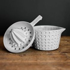 two white colanders sitting on top of a wooden table