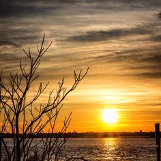 the sun is setting over some water and trees