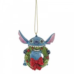 a christmas ornament hanging on a chain with a wreath and an image of stitch