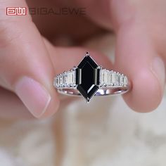 a woman's hand holding a black and white diamond ring