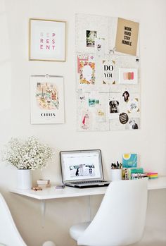 a laptop computer sitting on top of a white desk next to a vase filled with flowers