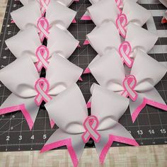 several pink and white ribbon bows on a cutting board with measuring tape in the background