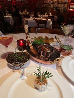 a table topped with plates and bowls filled with food next to glasses of wine on top of tables