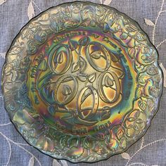 a decorative glass plate with ornate designs on the bottom and sides, sitting on a patterned tablecloth