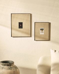 two vases sitting next to each other in front of some pictures on the wall