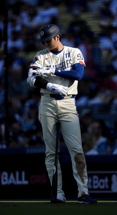 a baseball player is standing with his arms folded in front of him while holding a bat