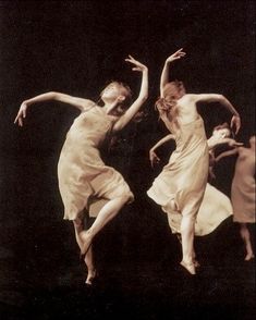 two women in white dresses are dancing on stage