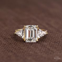 a three stone diamond ring on a brown surface