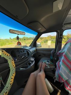 a person is sitting in the back seat of a vehicle with their feet on the steering wheel